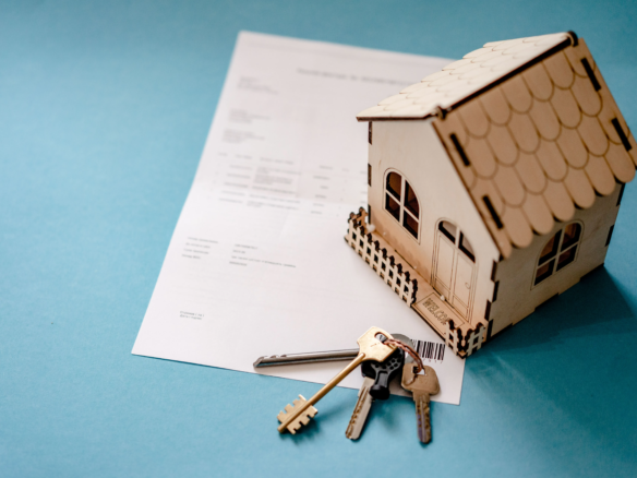 House model, keys and paperwork showing the process of selling a house.