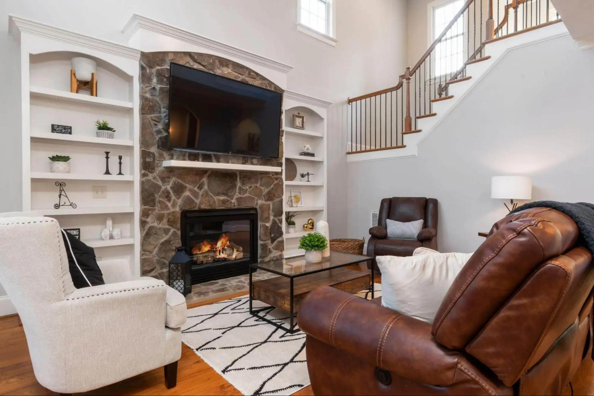 Living room with stone fireplace, built-in shelving and staircase in a family home